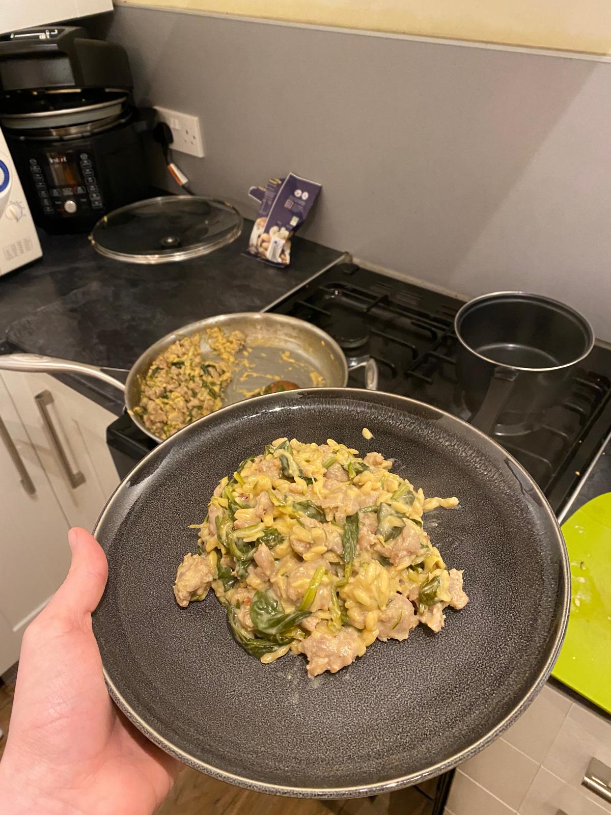 A picture of creamy orzo with sausage, spinach and shredded courgette